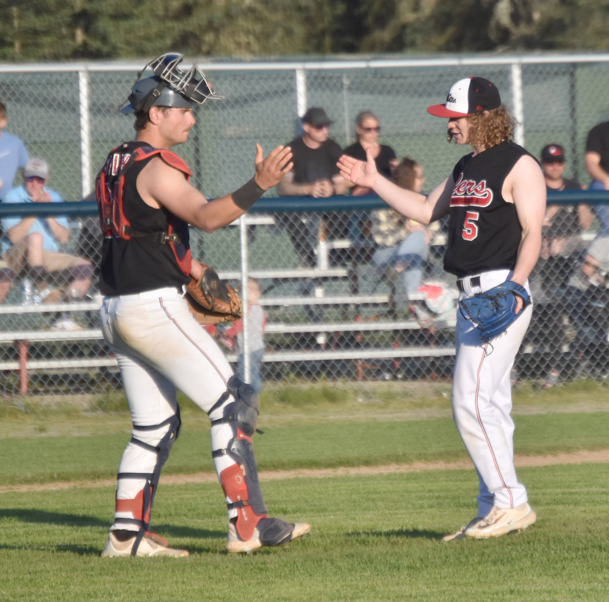 Peninsula Oilers catcher Braden Smith and pitcher Mose Hayes celebrate a victory over the Anchorage Glacier Pilots on Wednesday, July 31, 2024, at Coral Seymour Memorial Park in Kenai, Alaska. (Photo by Jeff Helminiak/Peninsula Clarion)