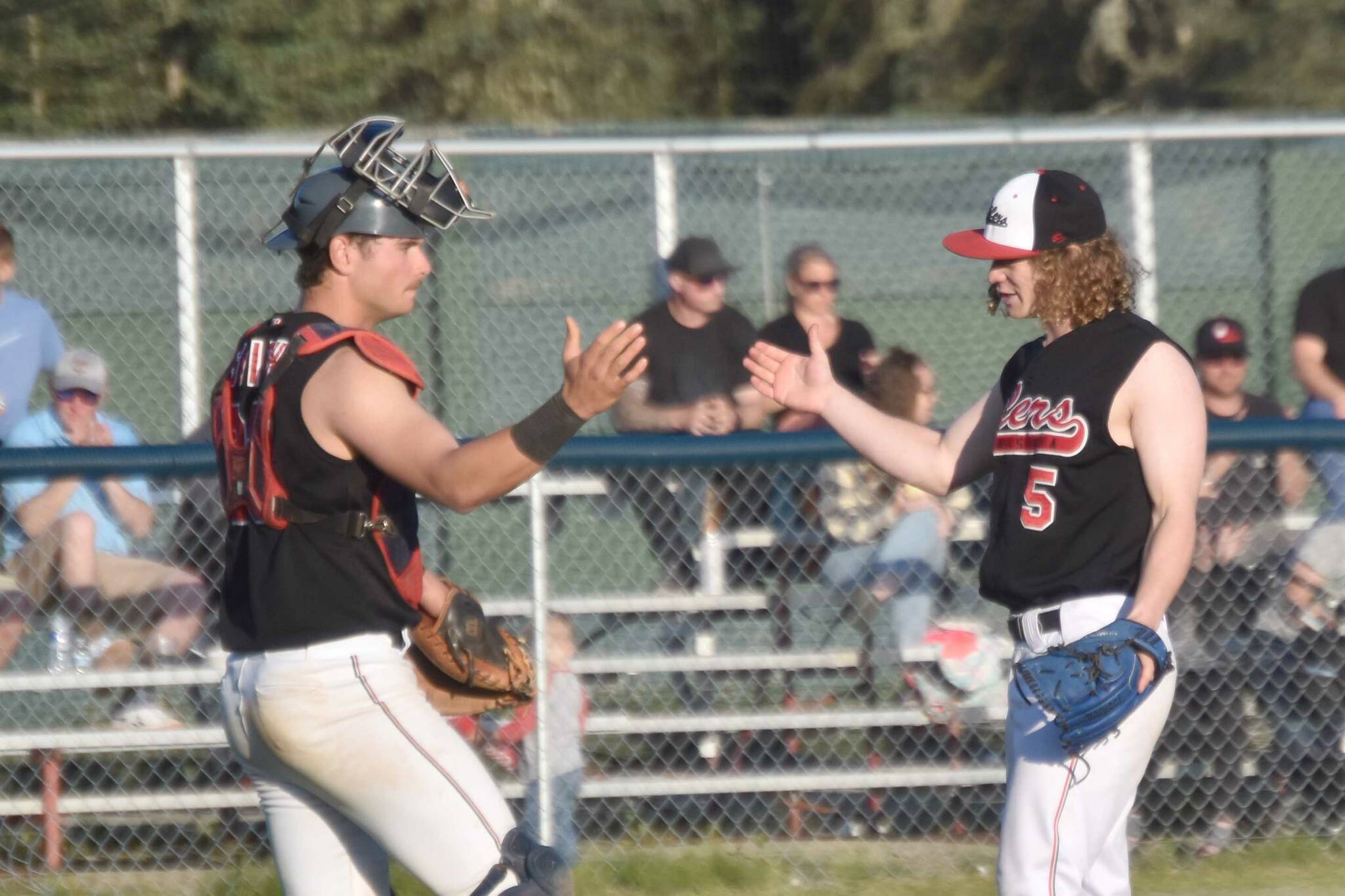 Peninsula Oilers catcher Braden Smith and pitcher Mose Hayes celebrate a victory over the Anchorage Glacier Pilots on Wednesday, July 31, 2024, at Coral Seymour Memorial Park in Kenai, Alaska. (Photo by Jeff Helminiak/Peninsula Clarion)