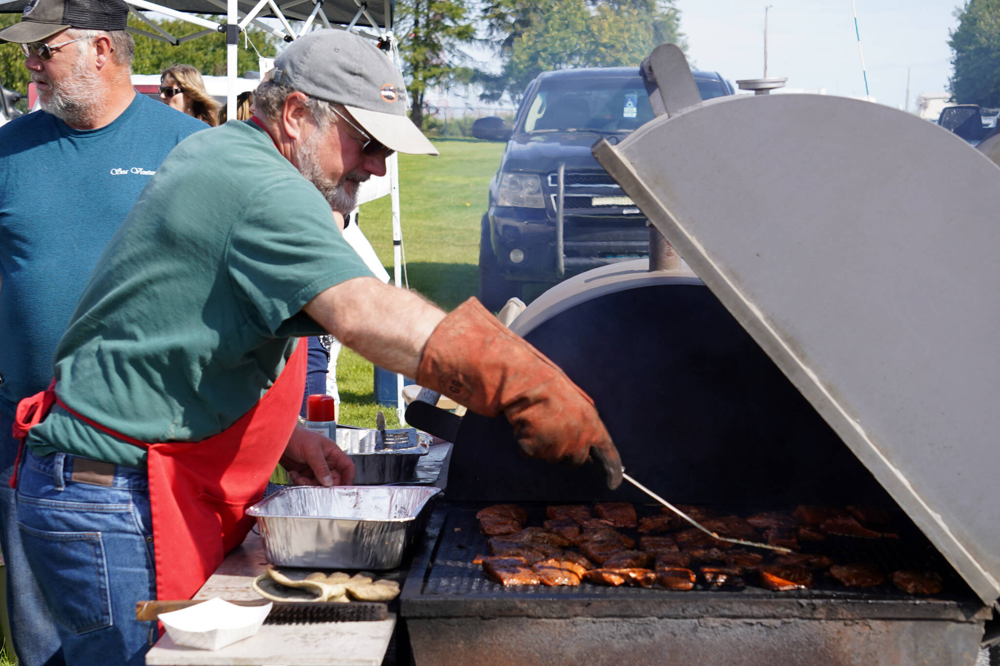 Teague Vanek barbecues salmon during Industry Appreciation Day festivities at the Kenai softball greenstrip in Kenai, Alaska, on Saturday, Aug. 19, 2023. (Jake Dye/Peninsula Clarion)