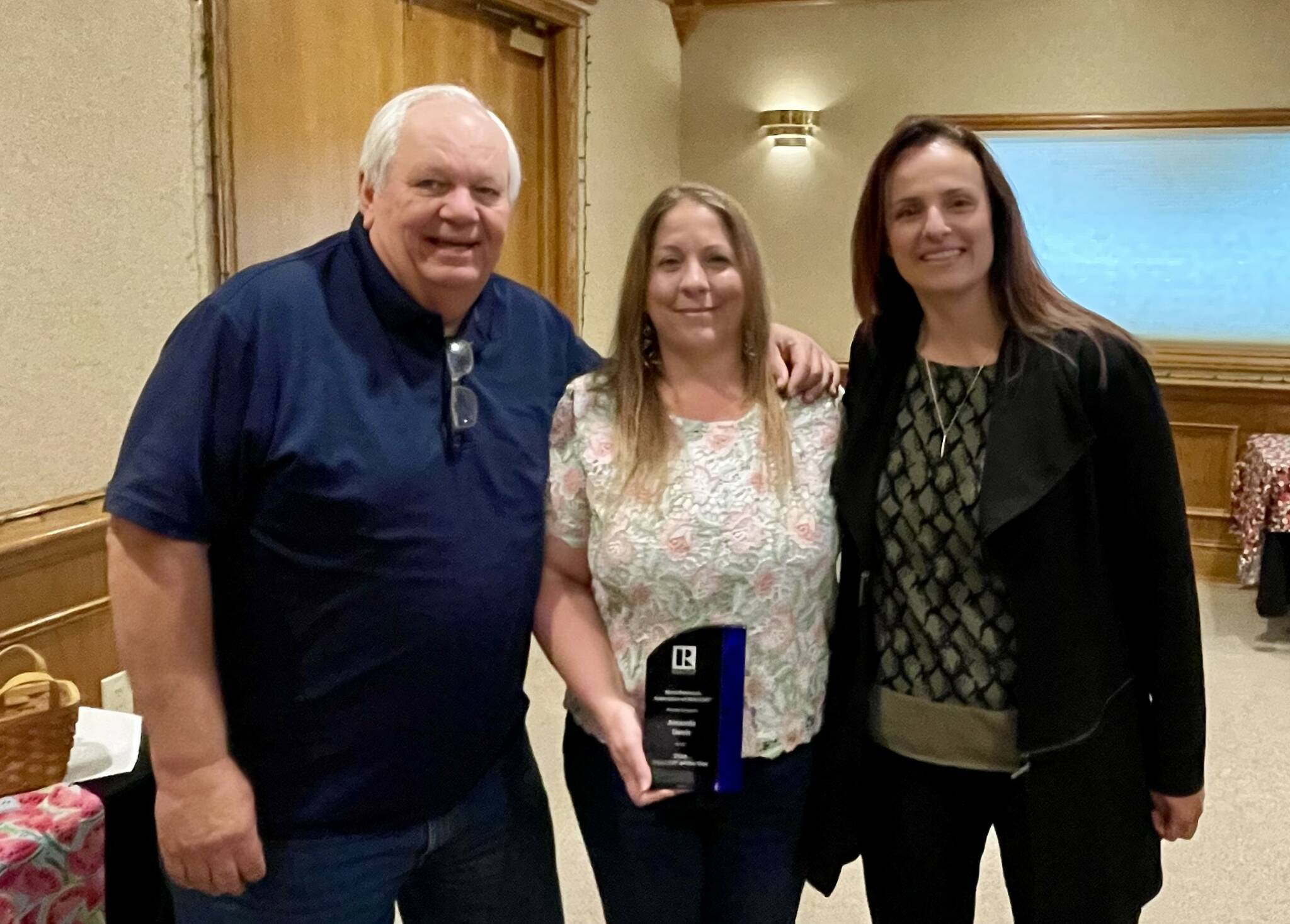 Realtor of the Year Amanda Davis, center, stands with Kenai Peninsula Association of Realtors President Randy Work and 2022 Realtor of the Year Natalia Aulenbacher on Thursday, Aug. 8, 2024 in Kenai, Alaska. (Photo provided by Kenai Peninsula Association of Realtors)