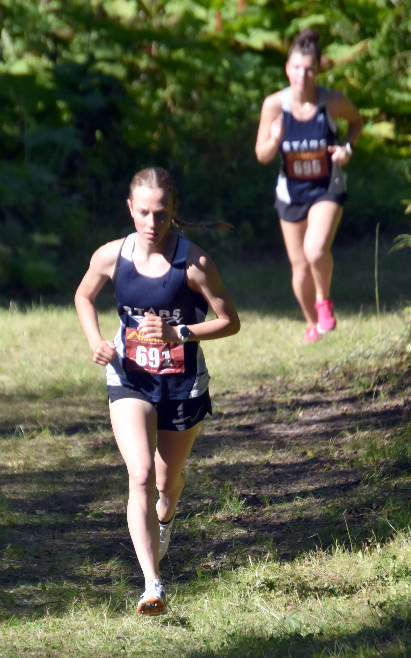 Soldotna’s Tania Boonstra leads Soldotna’s Annie Burns up a hill during the junior-senior girls race Monday, Aug. 19, 2024, at the Peninsula Class Races at Nikiski Middle-High School in Nikiski, Alaska. (Photo by Jeff Helminiak/Peninsula Clarion)