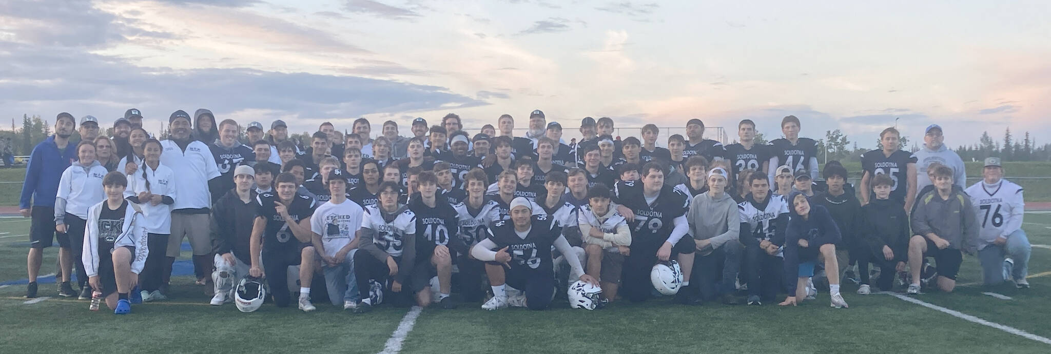 Current and former players and staff pose with head coach Galen Brantley Jr. after he set the new record for wins by an Alaska coach Friday, Sept. 6, 2024, at Justin Maile Field at Soldotna High School in Soldotna, Alaska. (Photo by Jeff Helminiak/Peninsula Clarion)