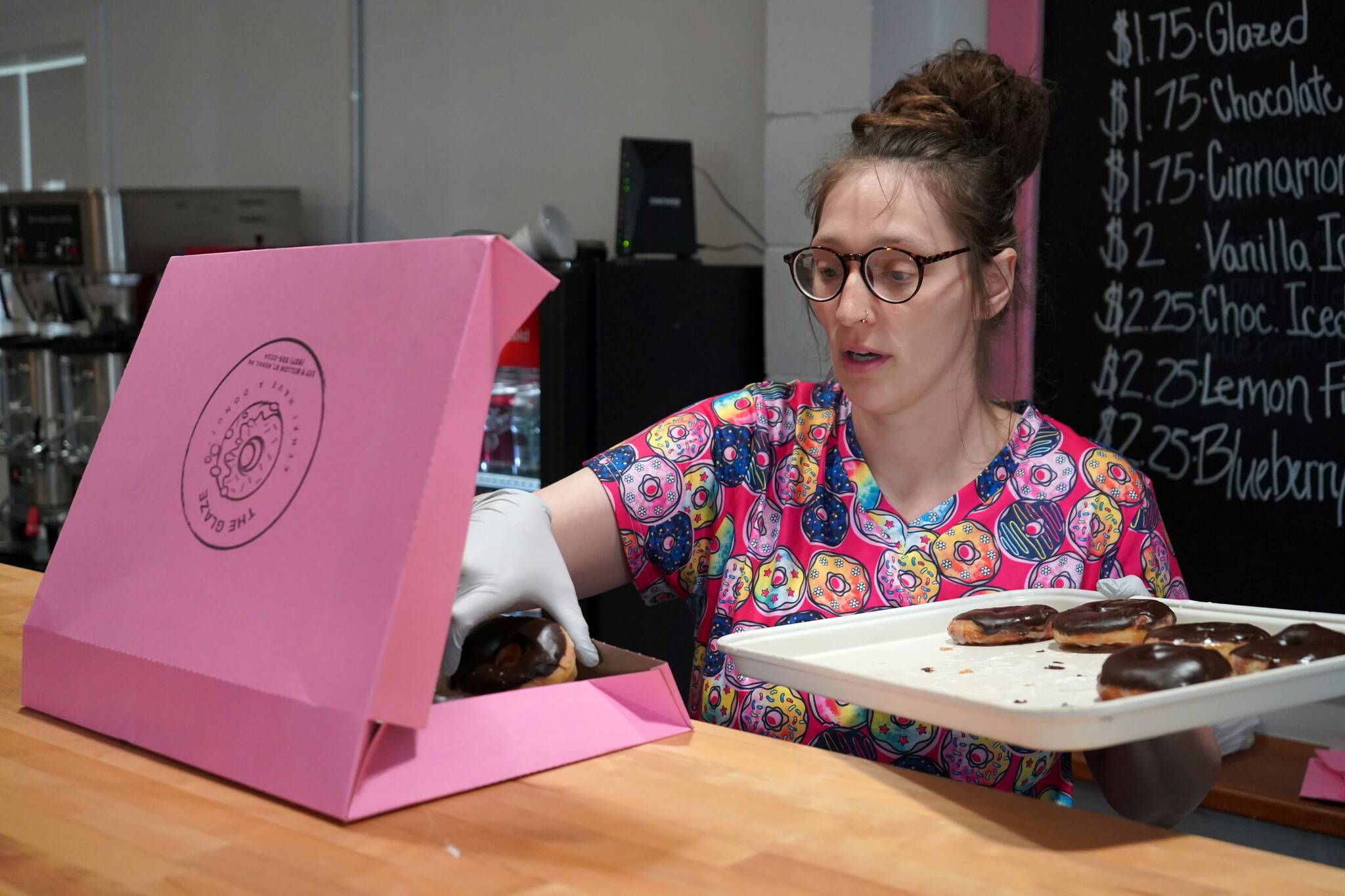 Abi Gutierrez fills a box of doughnuts during a ribbon-cutting event for The Glaze in Kenai, Alaska, on Wednesday, Sept. 4, 2024. (Jake Dye/Peninsula Clarion)