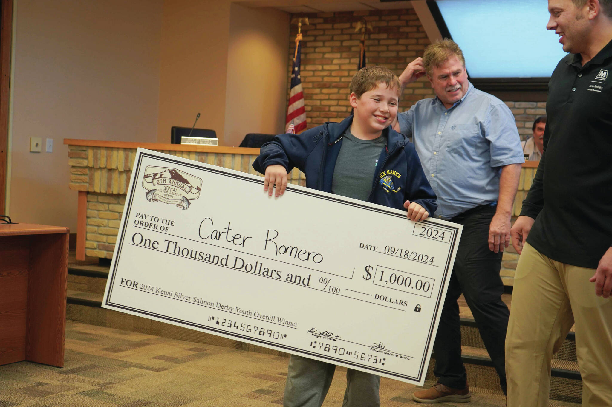 Jake Dye/Peninsula Clarion
Carter Romero is awarded a $1,000 novelty check for landing the youth grand-prize salmon in the Eighth Annual Kenai Silver Salmon Derby during a meeting of the Kenai City Council on Wednesday.