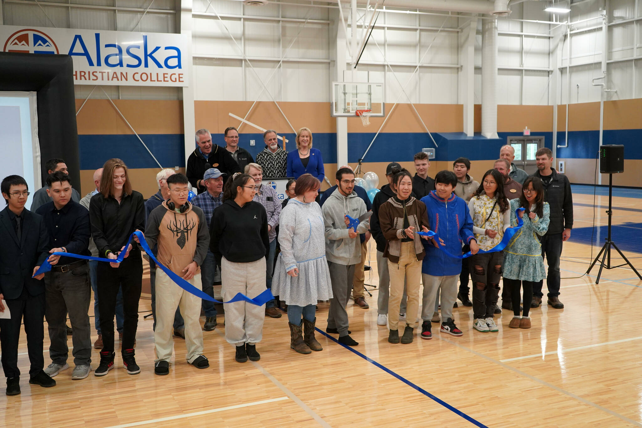 Alaska Christian College students, staff and other dignitaries gather as Styles Walker cuts the ribbon during a dedication ceremony for the college’s new athletic center at Alaska Christian College in Soldotna, Alaska, on Friday, Sept. 27, 2024. (Jake Dye/Peninsula Clarion)