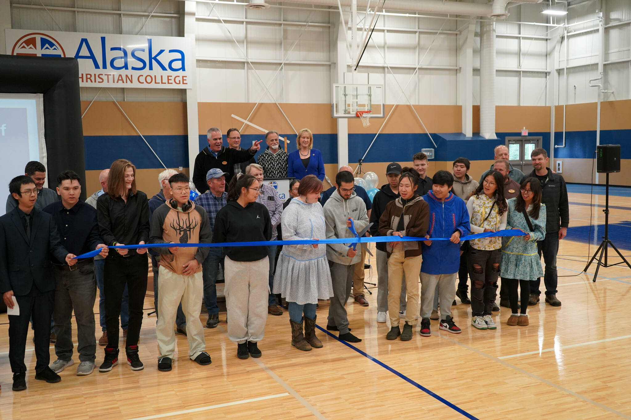 Alaska Christian College students, staff and other dignitaries gather as Styles Walker cuts the ribbon during a dedication ceremony for the college’s new athletic center at Alaska Christian College in Soldotna, Alaska, on Friday, Sept. 27, 2024. (Jake Dye/Peninsula Clarion)