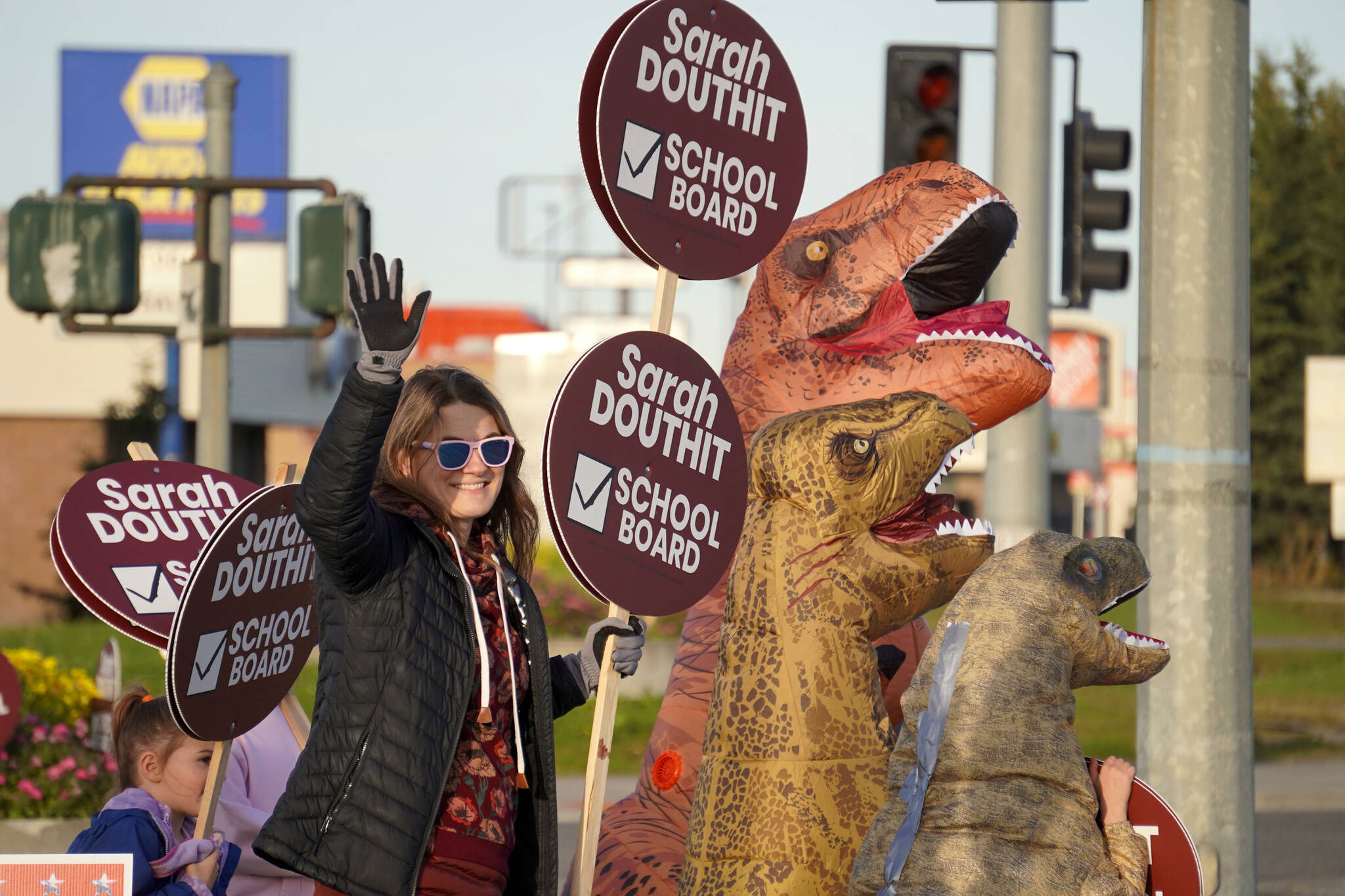 Board of Education candidate Sarah Douthit and her supporters wave signs at the side of the Kenai Spur Highway in Kenai, Alaska, on Tuesday, Oct. 1, 2024. (Jake Dye/Peninsula Clarion)