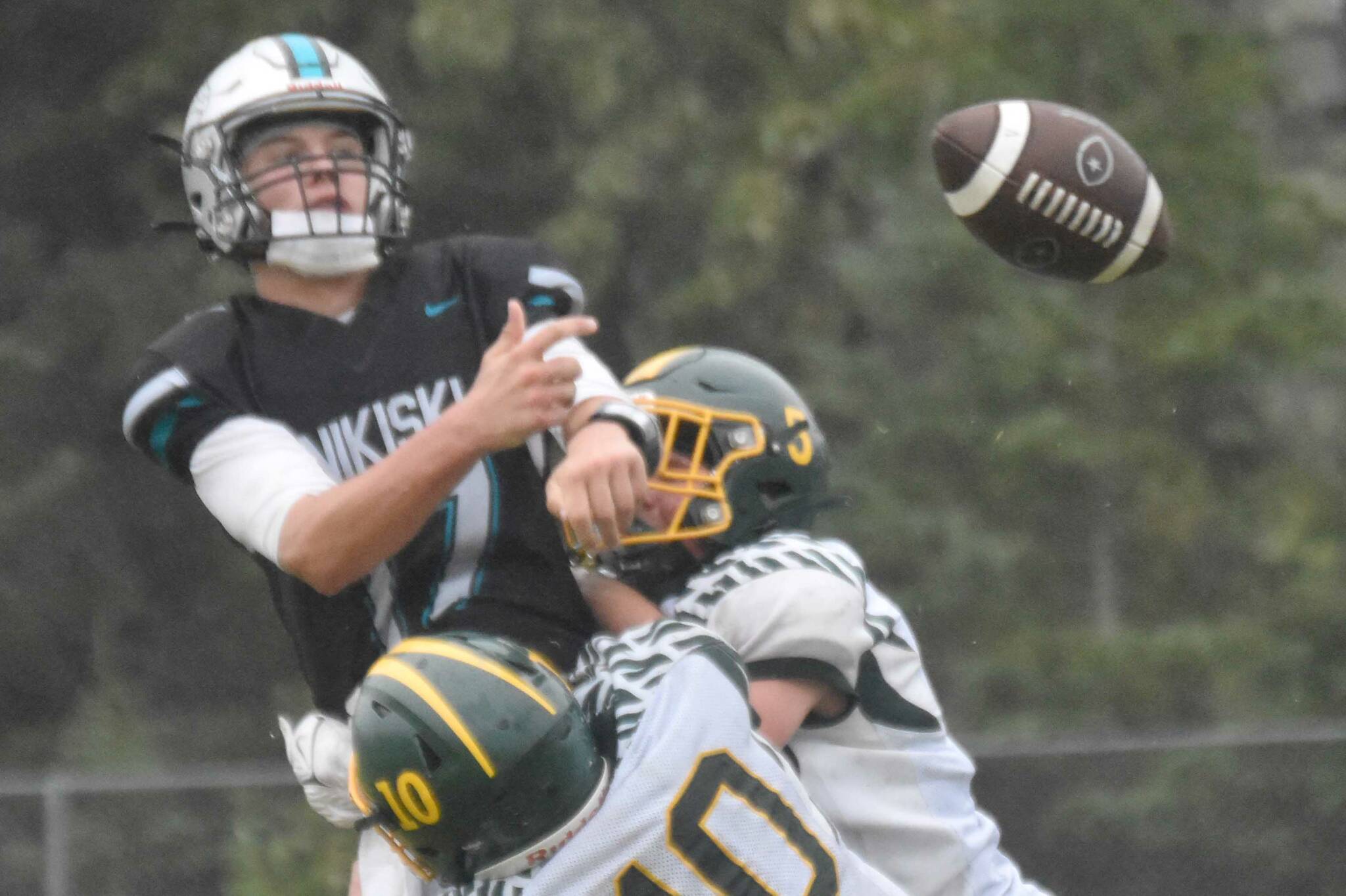 Nikiski's Ethan Ellis passes under pressure from Seward's Ronan Bickling and Emerson Cross (10) on Saturday, Aug. 17, 2024, at Nikiski Middle-High School in Nikiski, Alaska. (Photo by Jeff Helminiak/Peninsula Clarion)