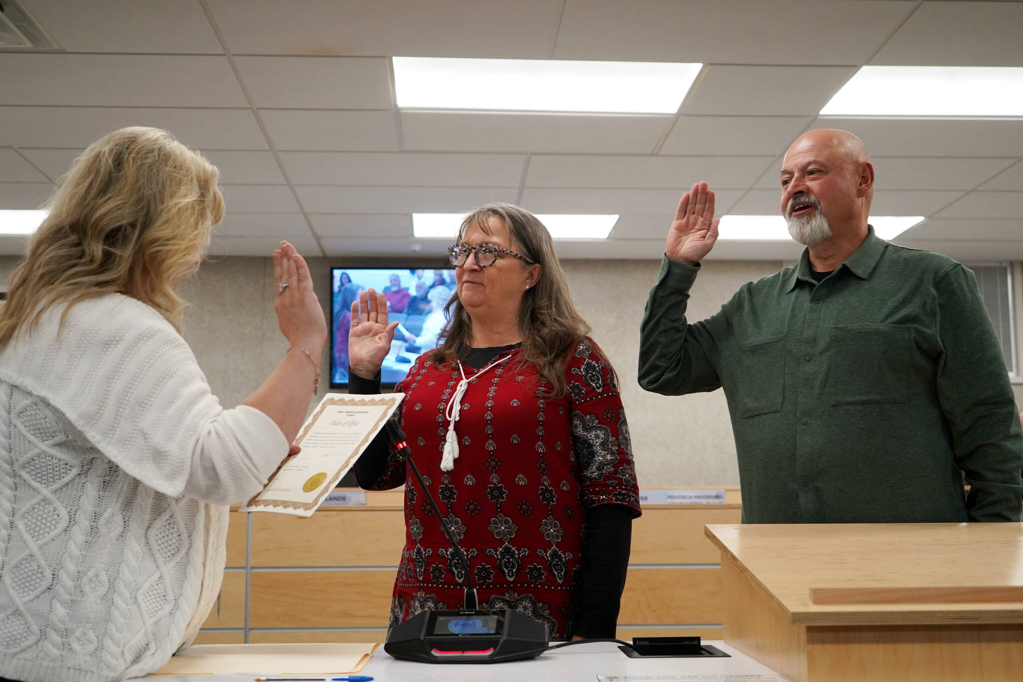 Borough Clerk Michele Turner administers oaths of office to Cindy Ecklund and James Baisden during a meeting of the Kenai Peninsula Borough Assembly in Soldotna, Alaska, on Tuesday, Oct. 8, 2024. Ecklund was reelected and Baisden was elected to the assembly during the Oct. 1 election. (Jake Dye/Peninsula Clarion)