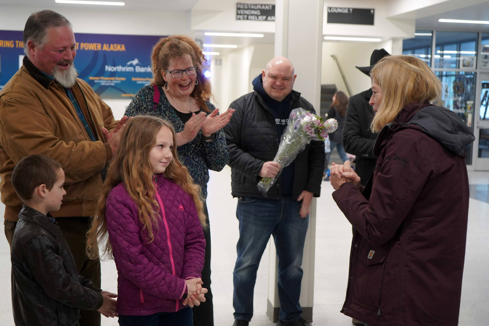 Rose Burke, center left, is celebrated for winning the U.S. Capitol Christmas Tree essay contest by U.S. Senator Lisa Murkowski, right, at the Kenai Municipal Airport in Kenai, Alaska, on Friday, Nov. 1, 2024. (Jake Dye/Peninsula Clarion)