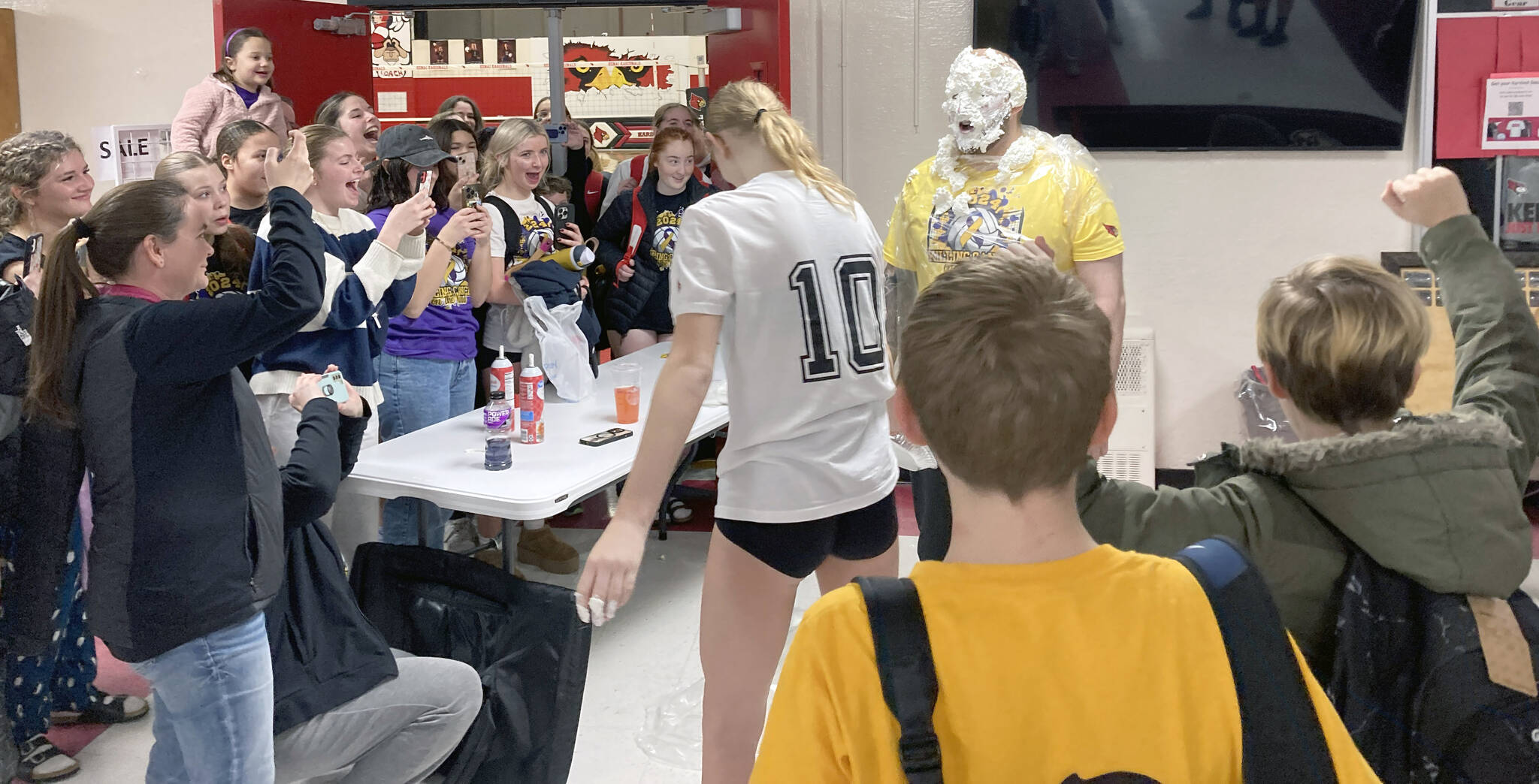 Soldotna's Cassidy Kruse hits Soldotna head coach Luke Baumer with a pie as part of the Killing Cancer on the Kenai event on Friday, Nov. 1, 2024, at Kenai Central High School in Kenai, Alaska. (Photo by Jeff Helminiak/Peninsula Clarion)