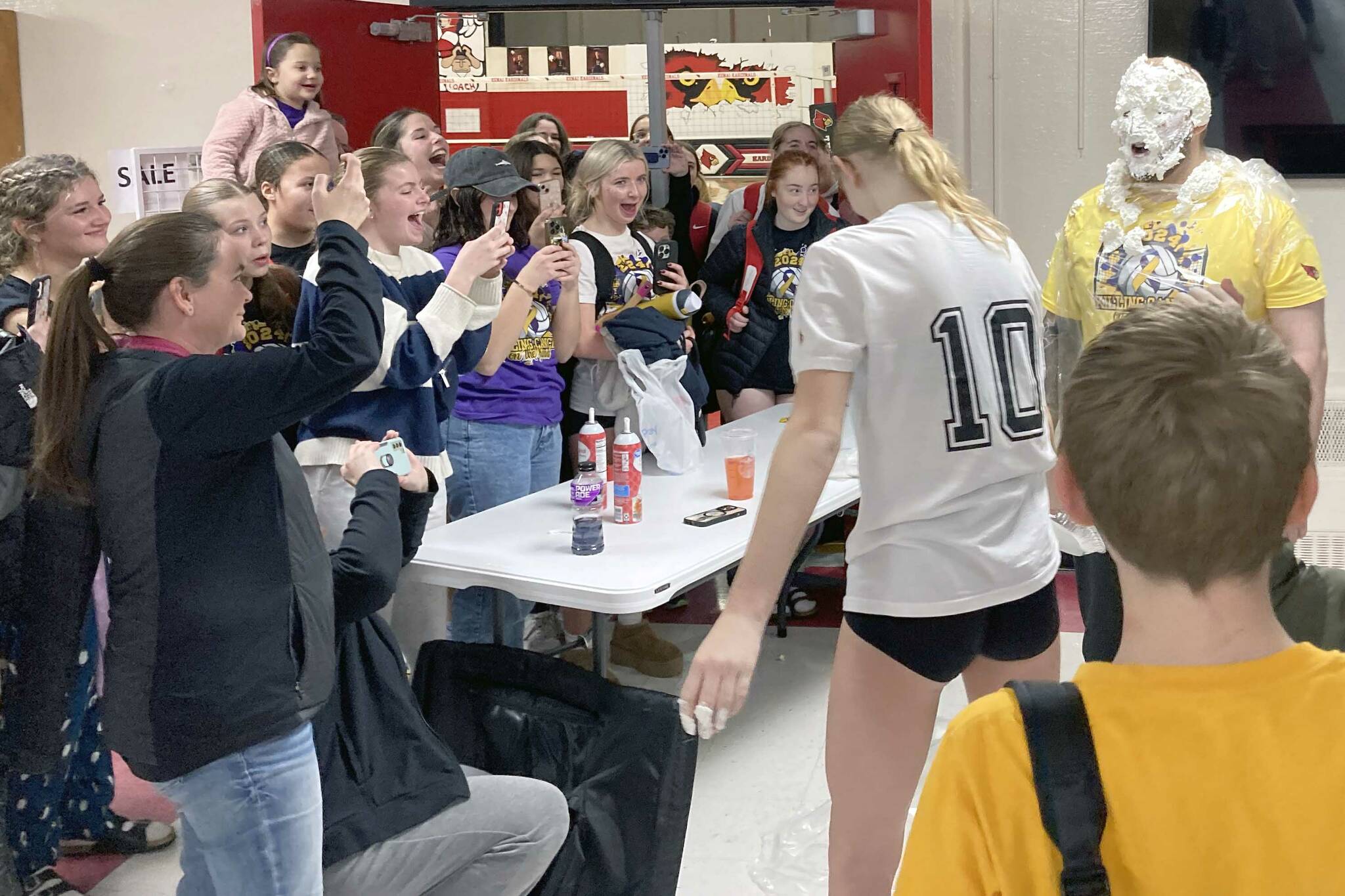 Soldotna's Cassidy Kruse hits Soldotna head coach Luke Baumer with a pie as part of the Killing Cancer on the Kenai event on Friday, Nov. 1, 2024, at Kenai Central High School in Kenai, Alaska. (Photo by Jeff Helminiak/Peninsula Clarion)