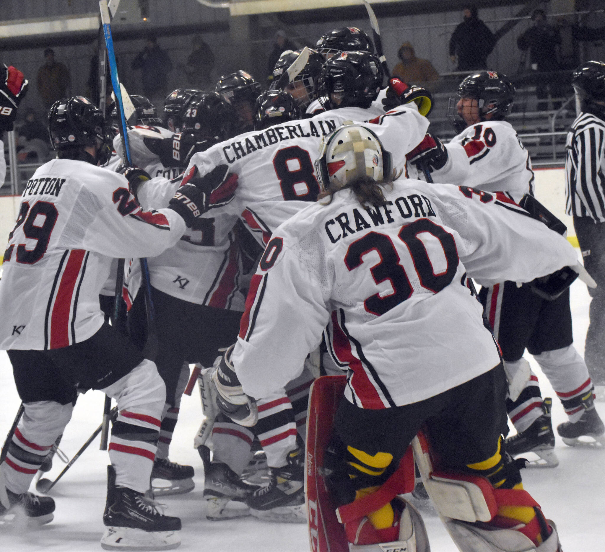 The Kenai Central hockey team mobs Logan Mese after Mese scored the game-winner in overtime against Chugiak on Thursday, Nov. 14, 2024, at the Kenai Multi-Purpose Facility in Kenai, Alaska. (Photo by Jeff Helminiak/Peninsula Clarion)