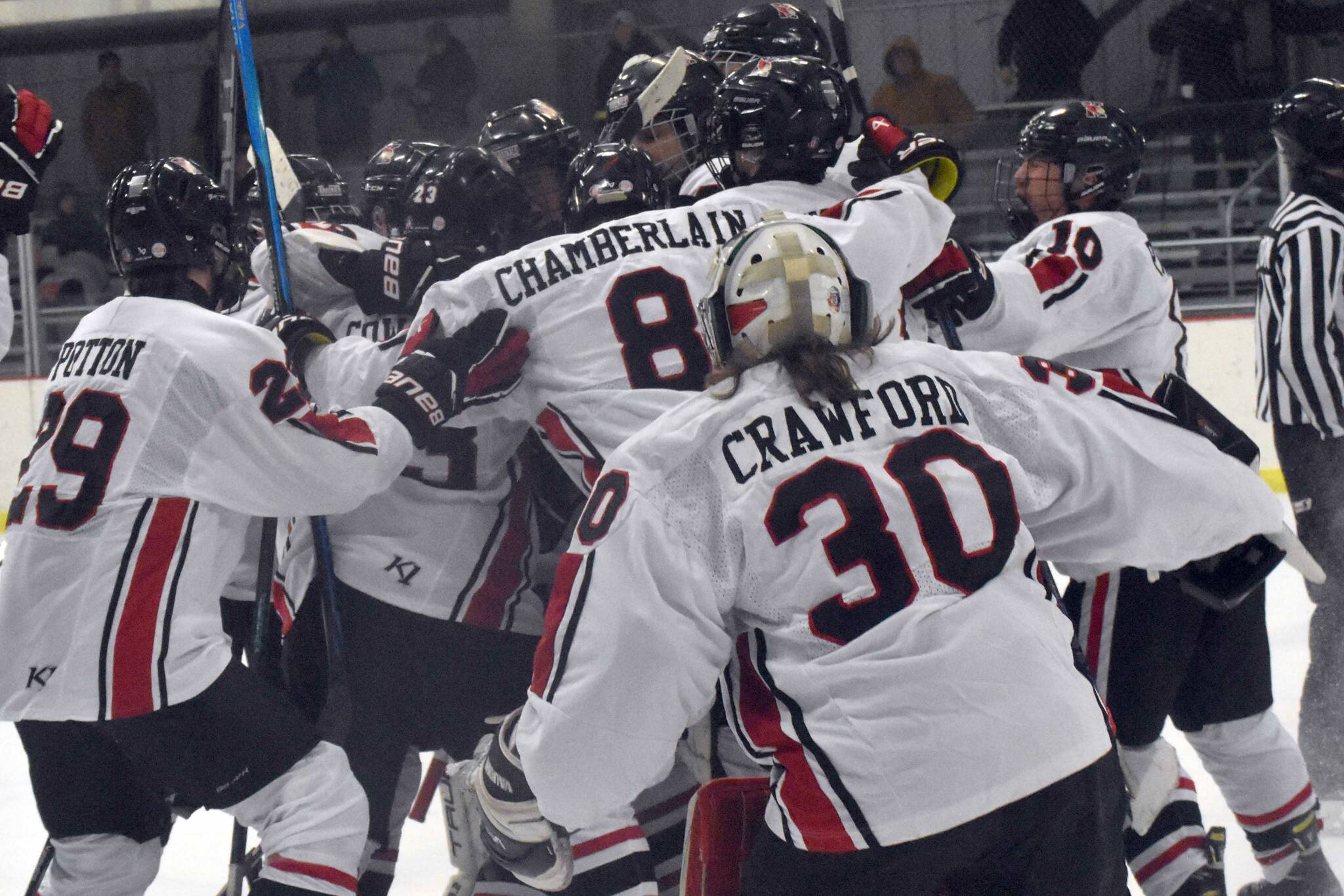 The Kenai Central hockey team mobs Logan Mese after Mese scored the game-winner in overtime against Chugiak on Thursday, Nov. 14, 2024, at the Kenai Multi-Purpose Facility in Kenai, Alaska. (Photo by Jeff Helminiak/Peninsula Clarion)