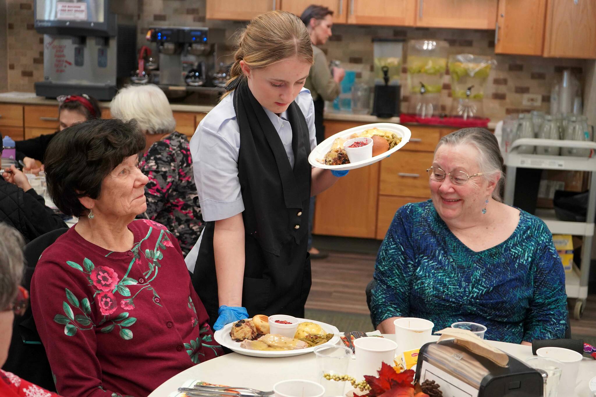 Kenai Civil Air Patrol Cadet Elodi Frisk delivers Thanksgiving meals to seniors during the Hilcorp Areawide Senior Thanksgiving Luncheon in the Kenai Senior Center banquet hall in Kenai, Alaska, on Friday, Nov. 22, 2024. (Jake Dye/Peninsula Clarion)