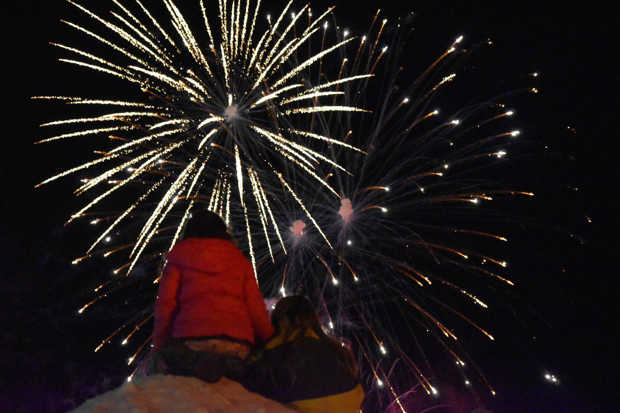 Children look up at exploding fireworks after the Electric Lights Parade at the Kenai Chamber of Commerce and Visitor Center in Kenai, Alaska, on Friday, Nov. 29, 2024. (Jonas Oyoumick/Peninsula Clarion)