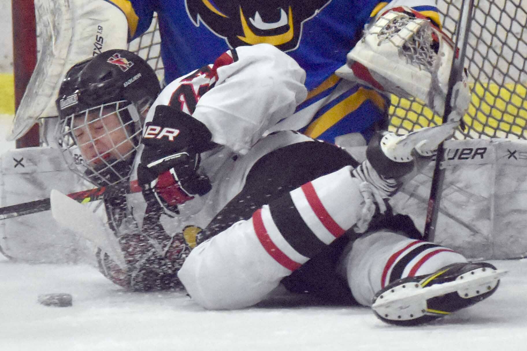 Kenai Central's Noah Hallam battles for the puck in front of Kodiak goalie Garrett Wood on Thursday, Dec. 12, 2024, at the Kenai Multi-Purpose Facility in Kenai, Alaska. (Photo by Jeff Helminiak/Peninsula Clarion)