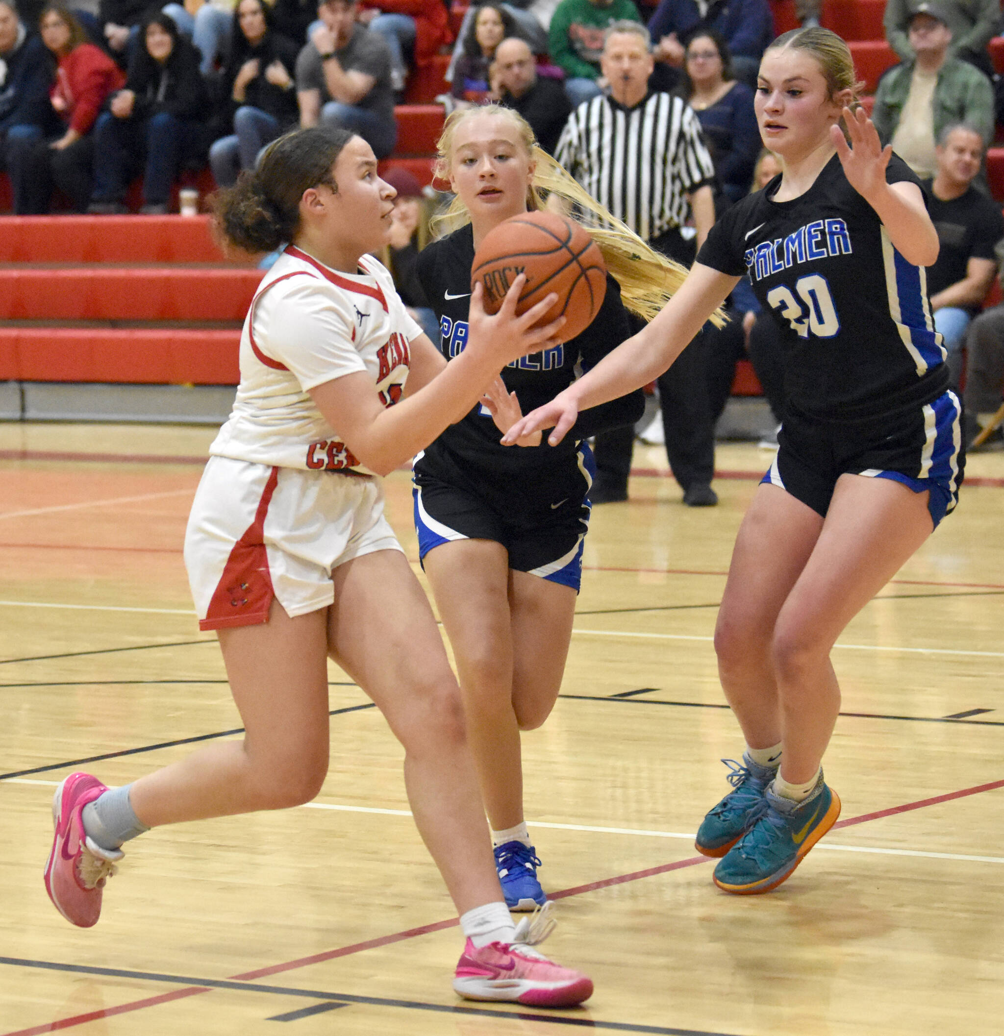 Kenai Central’s Bryleigh Williams drives against Palmer’s Kaylyn Miller and Jasmine Hephner on Thursday, Dec. 19, 2024, at Kenai Central High School in Kenai, Alaska. (Photo by Jeff Helminiak/Peninsula Clarion)