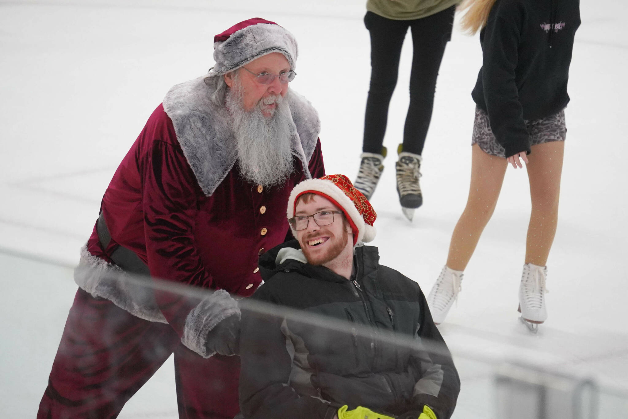 Santa Claus pushes a man across the ice during Skate with Santa at the Soldotna Regional Sports Complex in Soldotna, Alaska, on Saturday, Dec. 21, 2024. (Jake Dye/Peninsula Clarion)