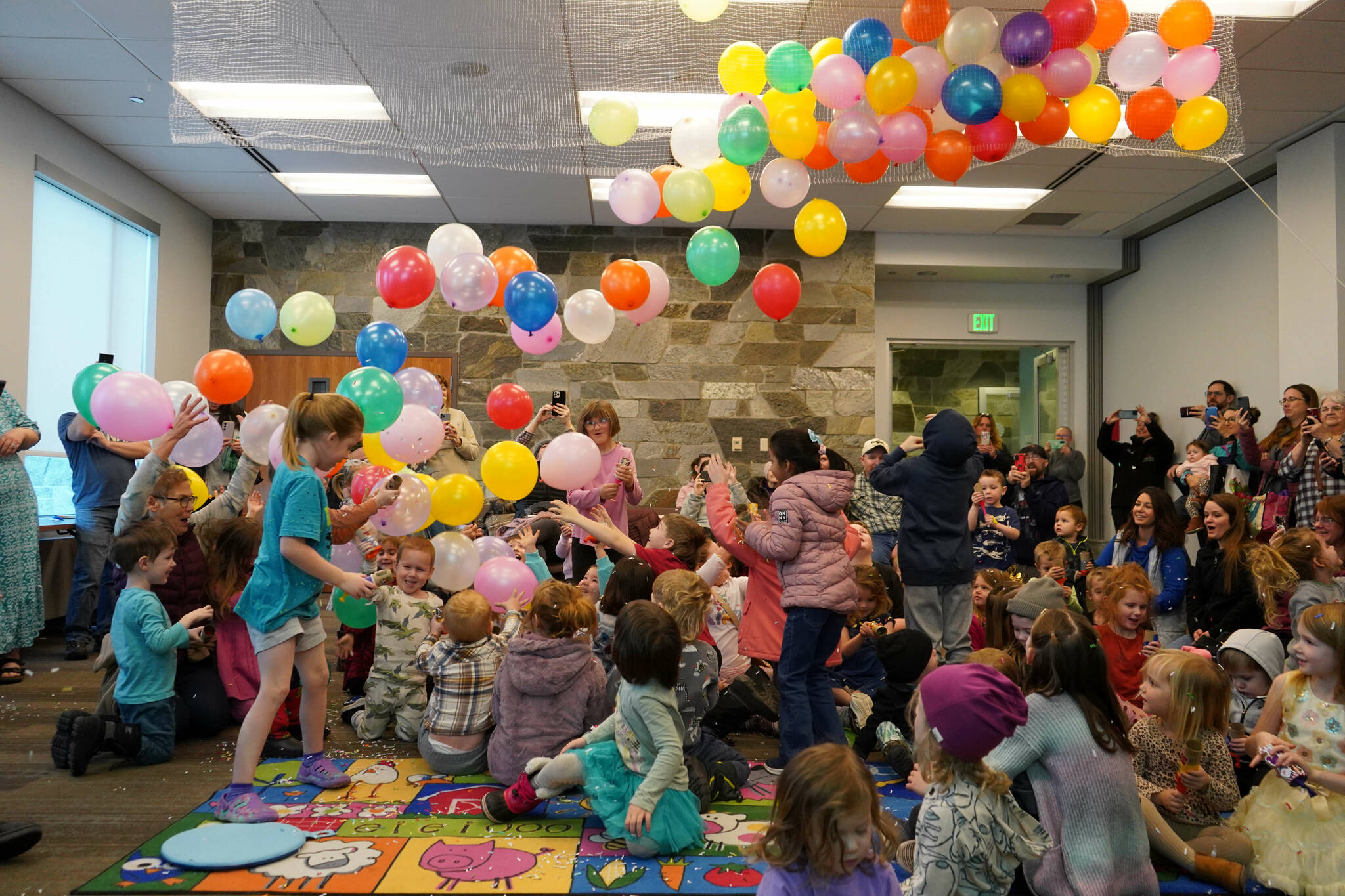 Balloons fall on dozens of children armed with confetti poppers during the Ninth Annual Noon-Year’s Eve Party at the Soldotna Public Library in Soldotna, Alaska, on New Year’s Eve, Tuesday, Dec. 31, 2024. (Jake Dye/Peninsula Clarion)