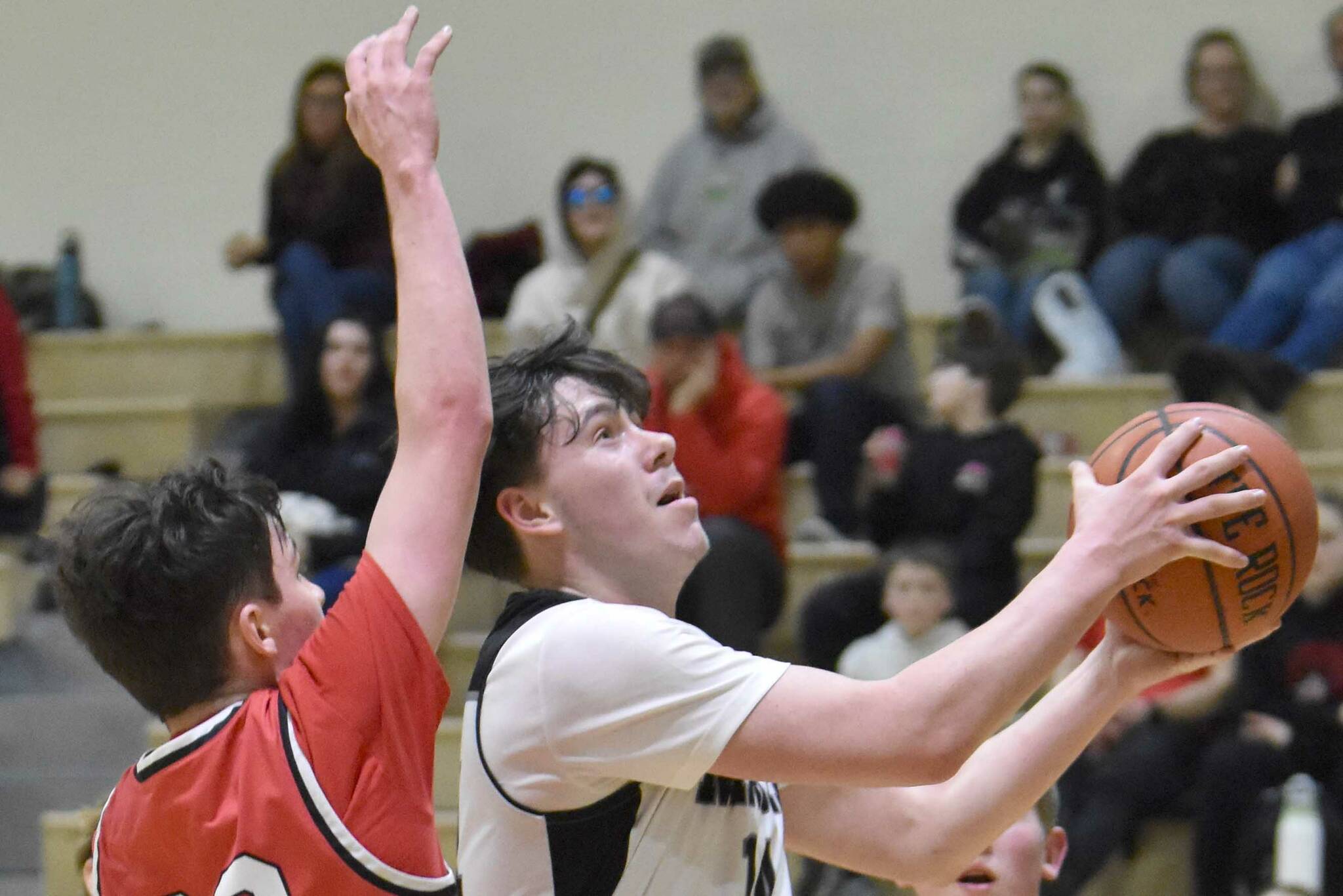 Nikiski's Kevin Love drives on Kenai Central's Ben Harris on Thursday, Jan. 9, 2025, at Nikiski Middle-High School in Nikiski, Alaska. (Photo by Jeff Helminiak/Peninsula Clarion)