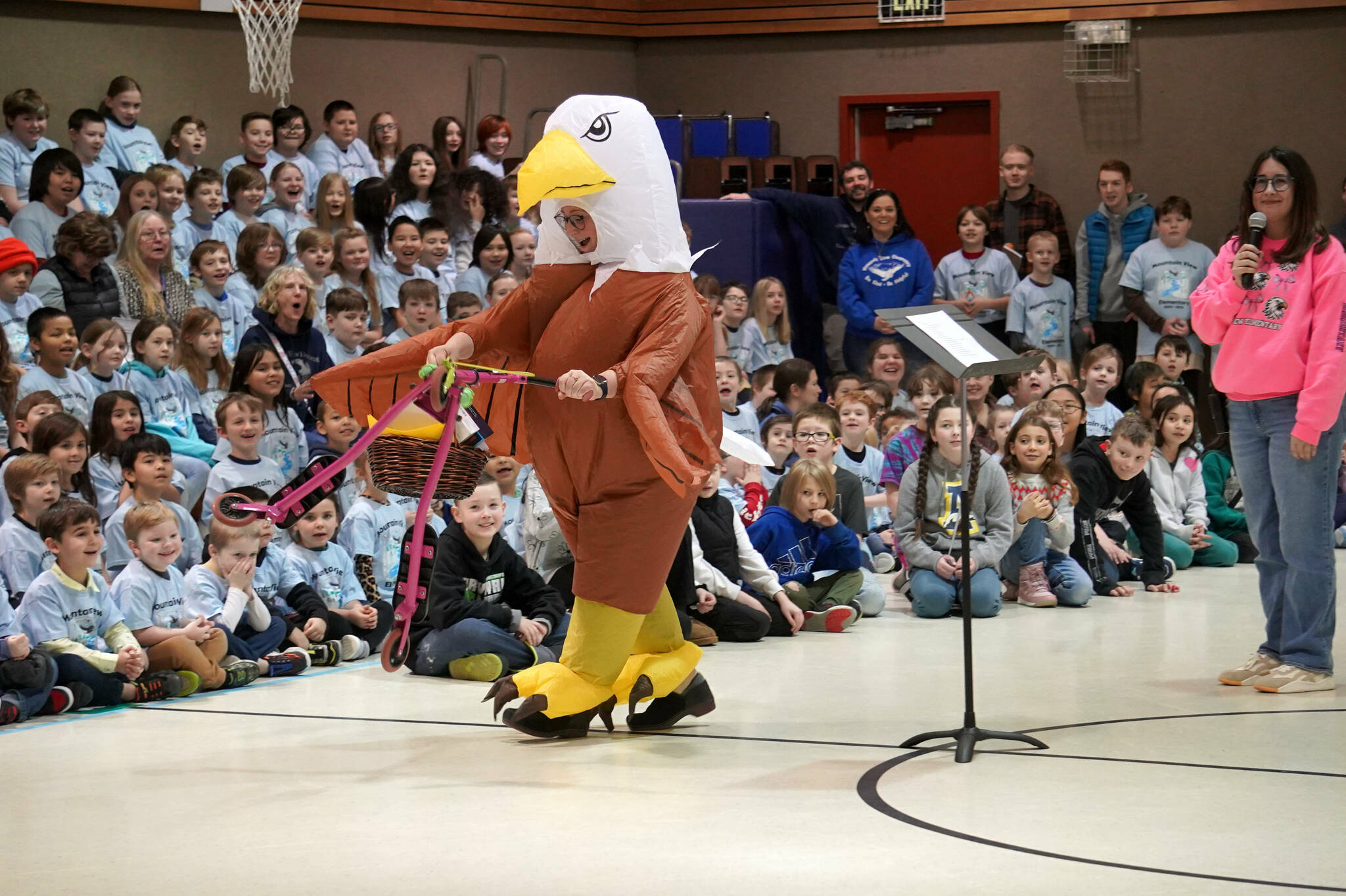 Aubrie Ellis, minutes before being named National Outstanding Assistant Principal of 2025 by the Alaska Association of Elementary School Principals, enters an awards assembly on a scooter and in a eagle costume at Mountain View Elementary School in Kenai, Alaska, on Friday, Jan. 10, 2025. (Jake Dye/Peninsula Clarion)