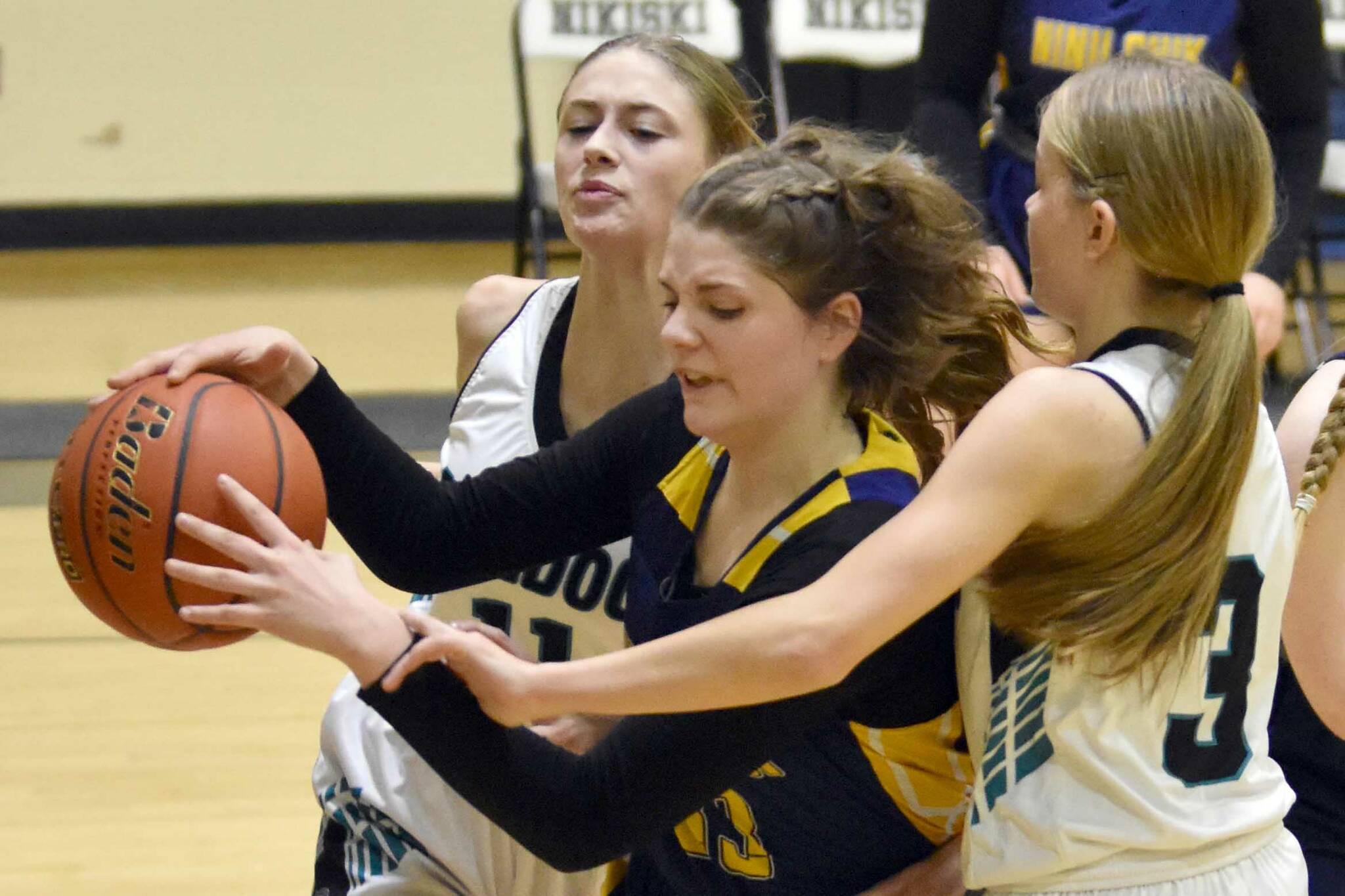 Ninilchik's Lucy Reynolds grabs the ball in front of Nikiski's Blakeley Jorgensen and Abby White at the 36th Annual Rus Hitchcock Nikiski Tip Off Tournament on Thursday, Jan. 16, 2025, at Nikiski Middle-High School in Nikiski, Alaska. (Photo by Jeff Helminiak/Peninsula Clarion)