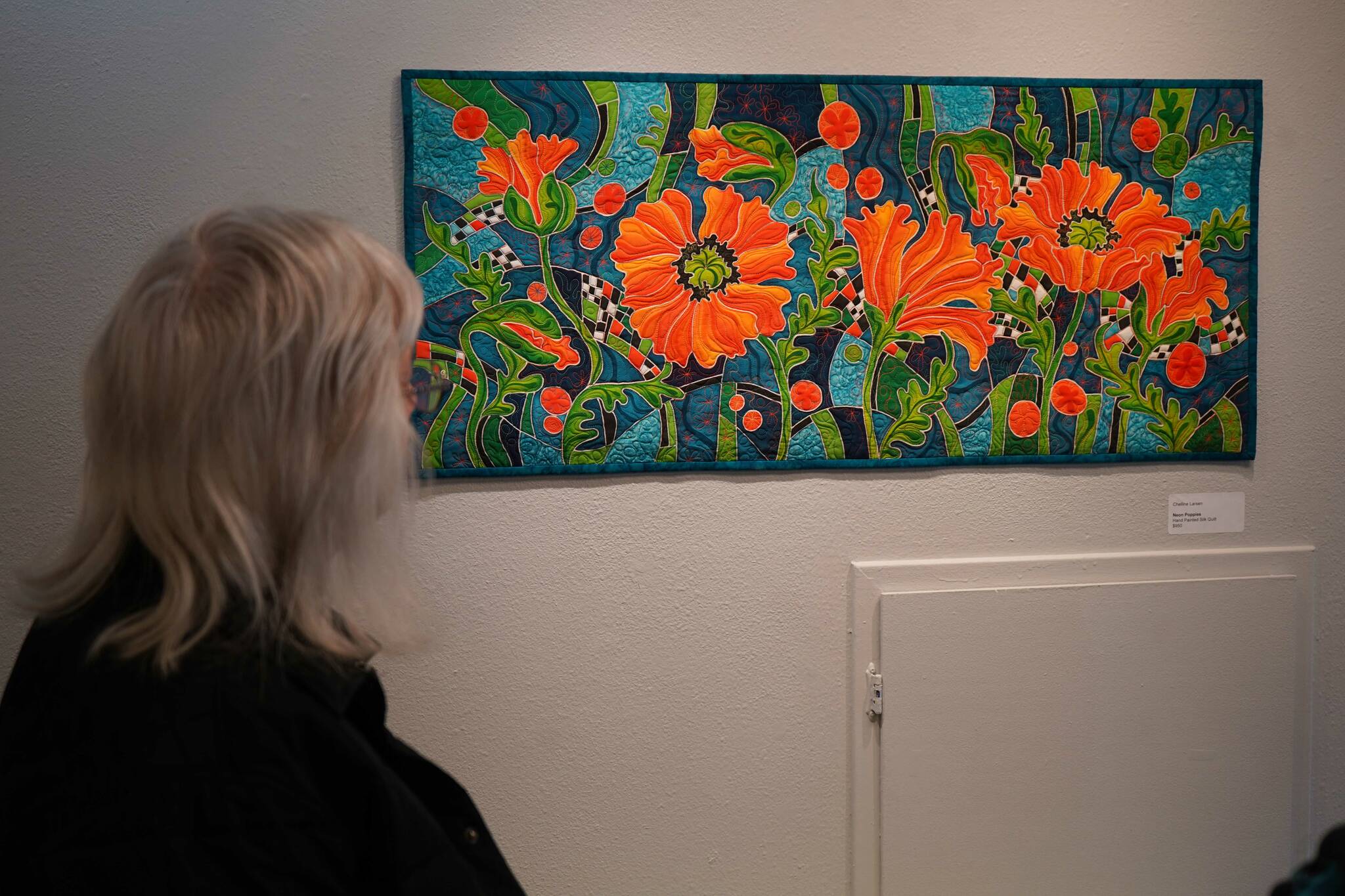 Attendees admire “Neon Poppies” by Chelline Larsen during the opening reception for “Infusion” at the Kenai Art Center in Kenai, Alaska, on Friday, March 7, 2025. (Jake Dye/Peninsula Clarion)