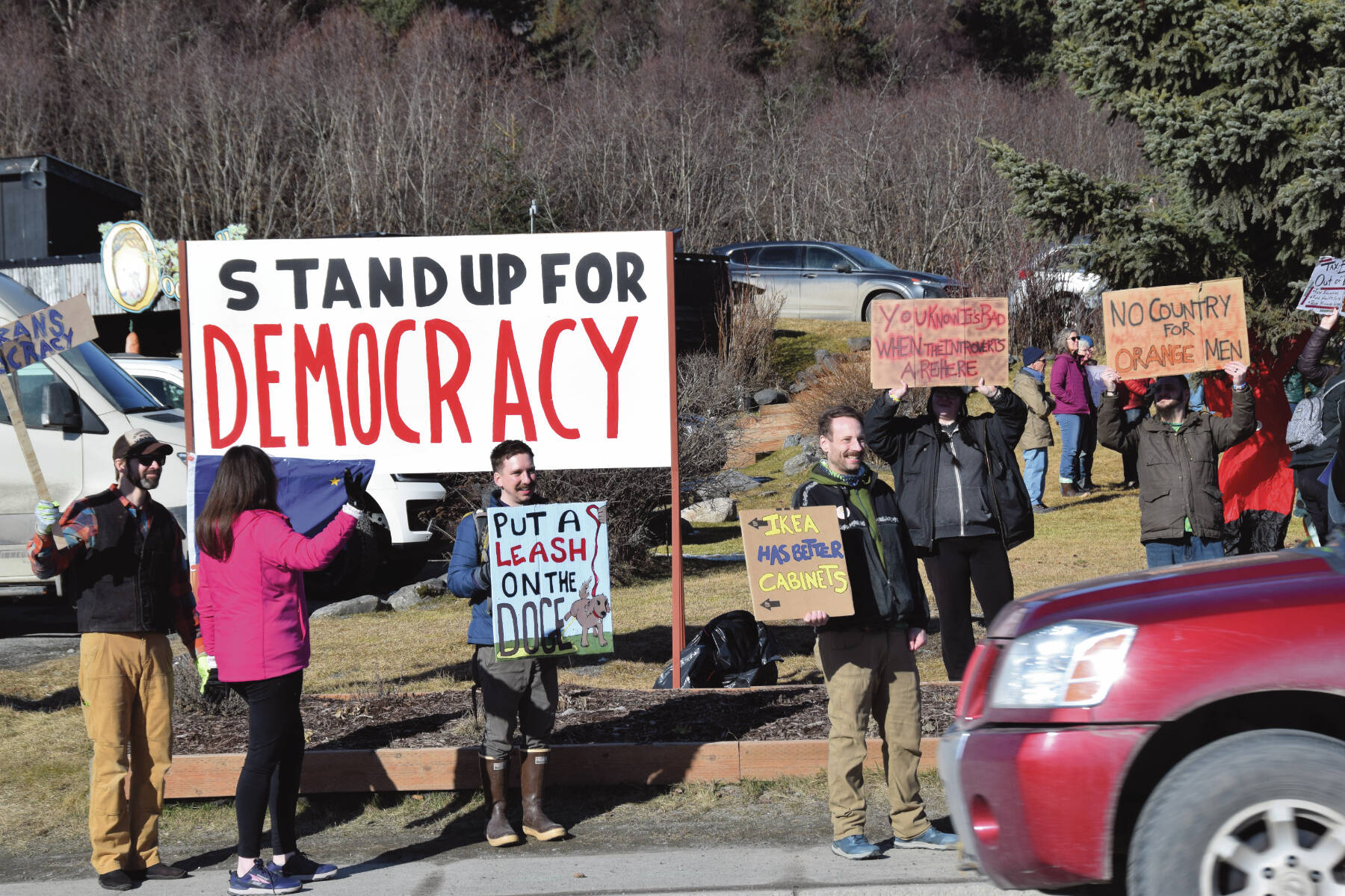 Community members hold up protest signs during the Stand for Democracy Rally on International Women’s Day, March 8, 2025, at WKFL Park in Homer, Alaska. (Chloe Pleznac/Homer News)